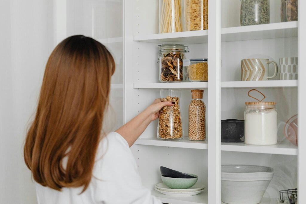 Woman organizing pantry shelves with kitchen storage containers