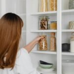 Woman organizing pantry shelves with kitchen storage containers
